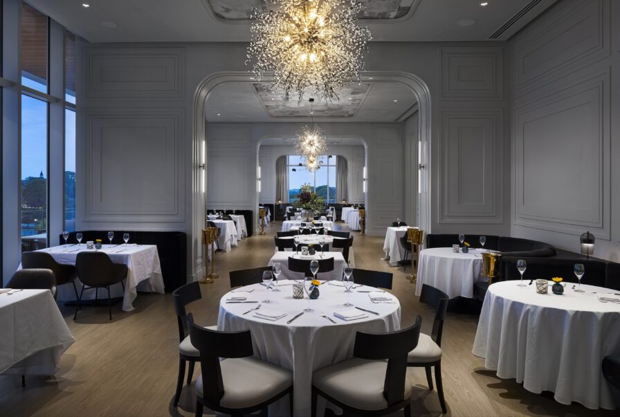 Elegant Italian dining experience awaits in this Atlanta restaurant, featuring round tables set with white tablecloths and chandeliers. Large windows offer stunning views, while ambient lighting creates a sophisticated atmosphere.