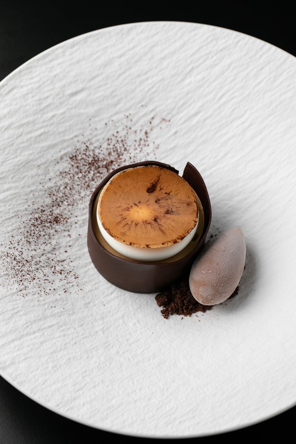 Indulge in this upscale dessert, where a luscious chocolate mousse is topped with a cookie and complemented by a scoop of rich chocolate ice cream, elegantly presented on a textured white plate. Perfect for savoring at an Italian dining experience in the heart of Atlanta.