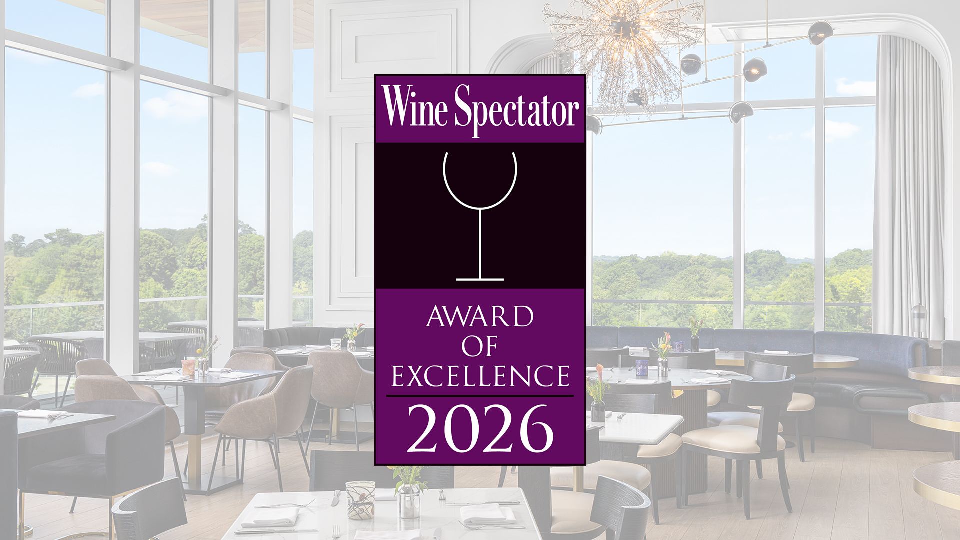 A restaurant dining room with large windows, featuring a "Wine Spectator Award of Excellence 2026" badge in the center.